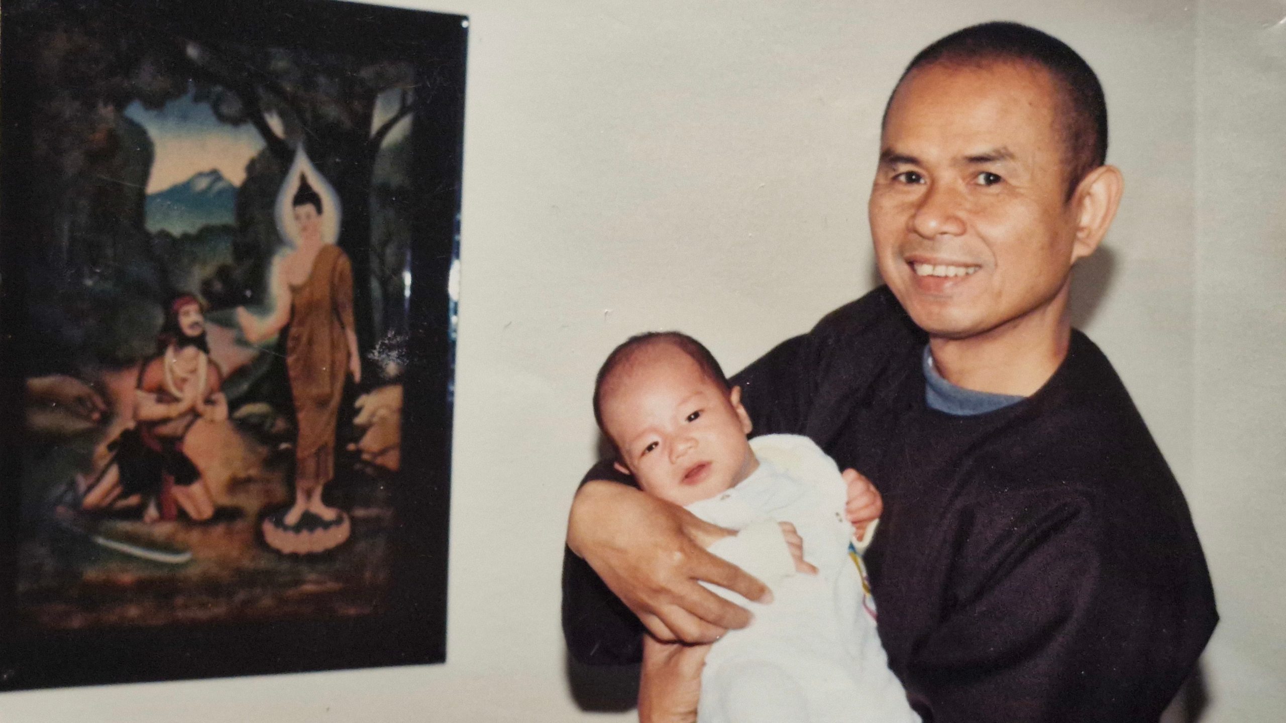 Young Thich Nhat Hanh holding a baby and smiling