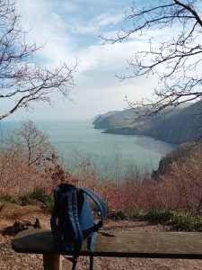 Rucksack on a bench with view of sea and hills in background