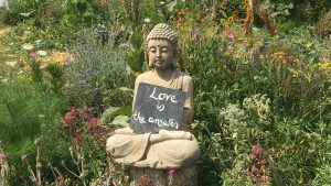 Buddha statue holding Love is the Way sign