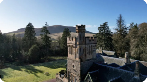 Aerial view of Wiston Lodge with hills and blue sky in background.