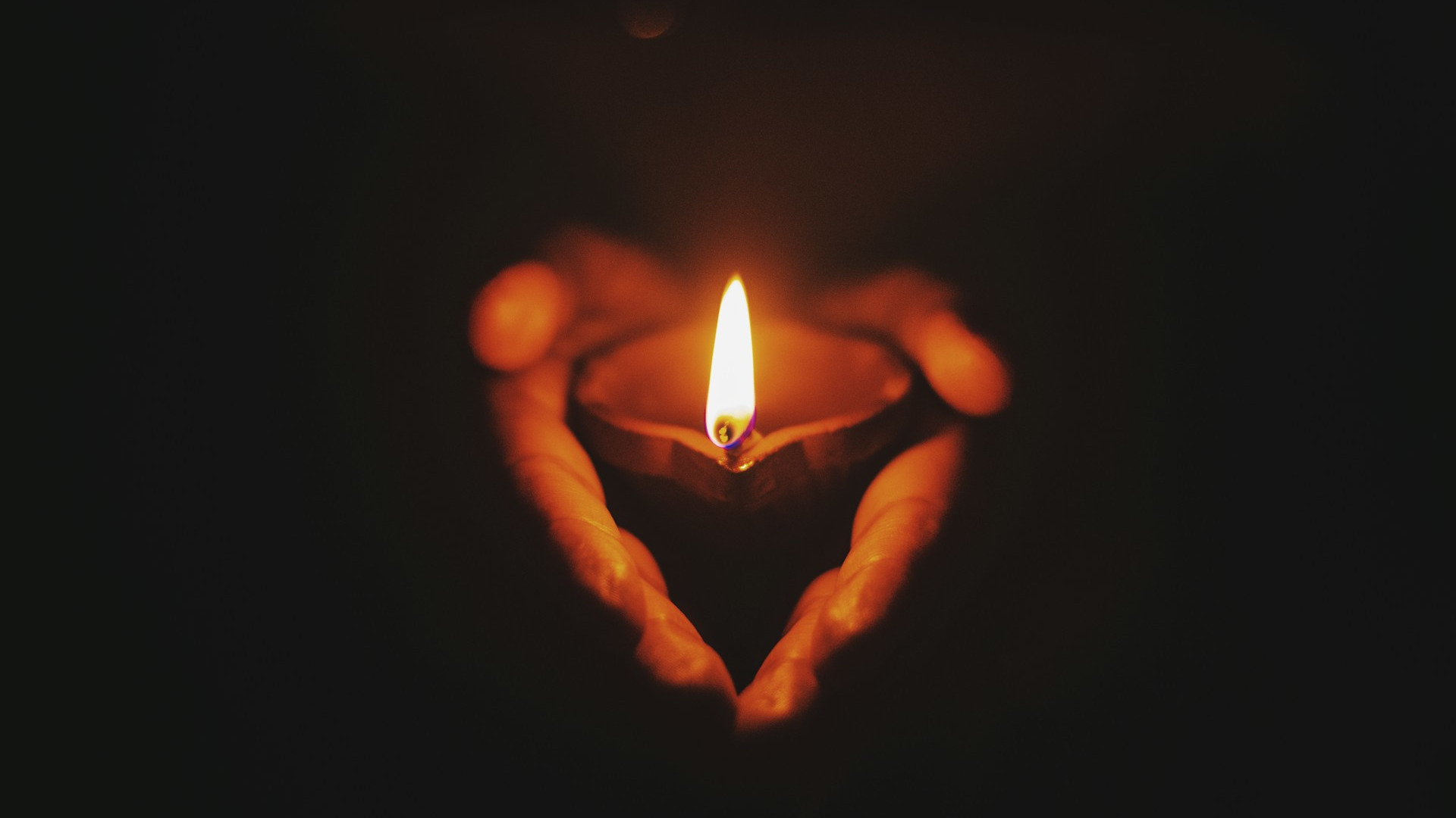 Candle being held in a holder against dark background